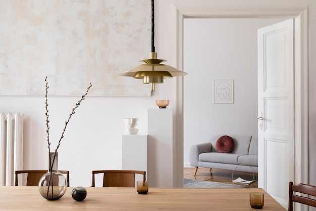 디자인 회색 소파, 복고풍 나무 테이블, 포스터 프레임, 장식, 카펫 및 우아한 가정 장식의 개인 액세서리를 모의하는 가정 공간의 세련된 스칸디 인테리어.