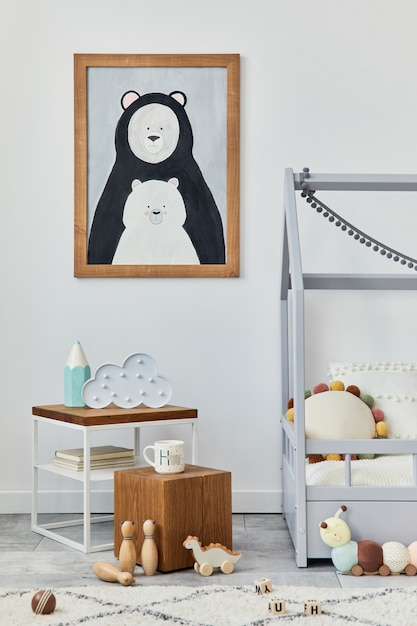 Elegante interno della stanza dei bambini scandinavi con finta cornice per poster, letto creativo, cubo di legno, peluche e giocattoli in legno e decorazioni tessili sospese. muro grigio, moquette sul pavimento. modello.