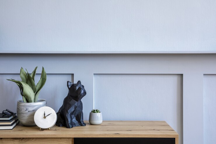 Stylish scandinavian composition with wooden commode, candle, succulent in pot, books, white clock, decoration, copy space and gray wood paneling in modern concept.