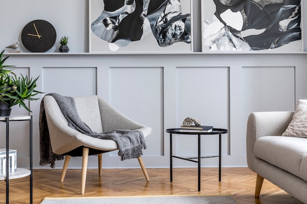 Stylish scandinavian home interior of living room with design gray sofa, armchair, marble stool, black coffee table, modern paintings, decoration, plant and elegant personal accessories in home decor.