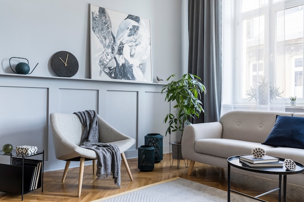 디자인 회색 소파, 안락 의자, 대리석 의자, 블랙 커피 테이블, 현대 그림, 장식, 식물 및 가정 장식의 우아한 개인 액세서리가있는 거실의 세련된 스칸디나비아 홈 인테리어.