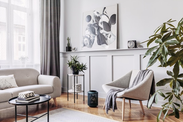 Stylish scandinavian home interior of living room with design gray sofa armchair marble stool black coffee table modern paintings decoration plant and elegant personal accessories in home decor