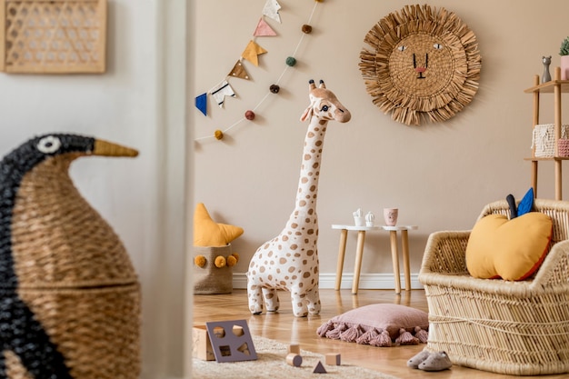 천연 장난감, 매달린 장식, 디자인 가구, 봉제 동물, 테디 베어 및 액세서리가있는 어린이 방의 세련된 스칸디나비아 인테리어. 베이지 색 벽. 아이 방의 인테리어 디자인.