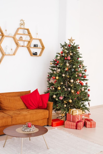 Stylish scandinavian living room with red sofa and red pillows on it christmas tree with gifts