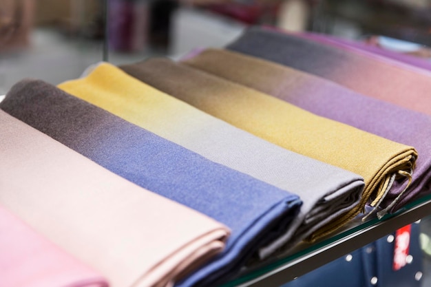 Stylish scarves and stoles in pastel colors on the counter. Close-up. Selective focus.