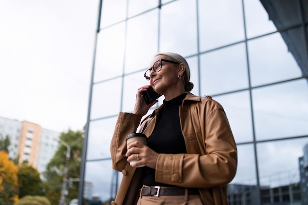 Стильная пожилая взрослая европейская деловая женщина на фоне стеклянного фасада офисного года