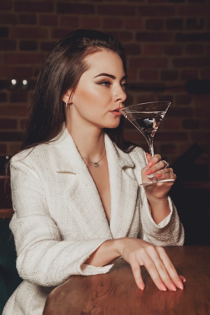 Стильная сексуальная женщина с бокалом мартини за столом