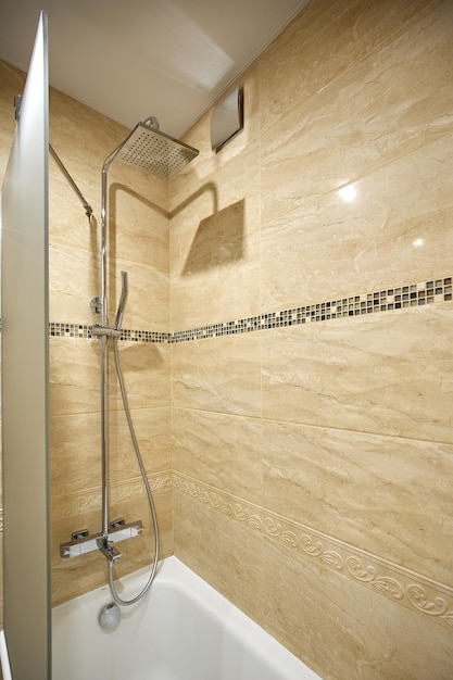 Stylish shower over bathtub with frosted glass in bathroom