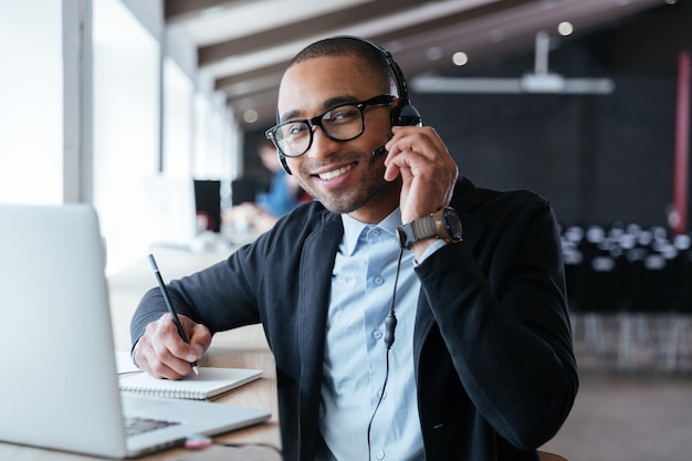 Elegante uomo d'affari intelligente che usa le cuffie durante il suo lavoro in ufficio