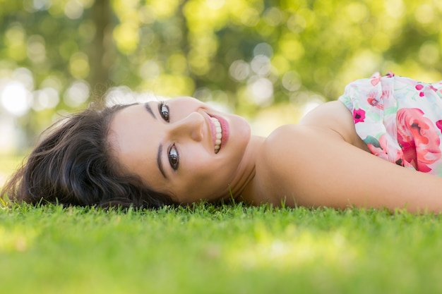 Stylish smiling brunette lying on a lawn