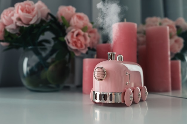 Stylish smoking aroma diffuser in the form of a steam locomotive on the table. Women's space, a cozy workplace.