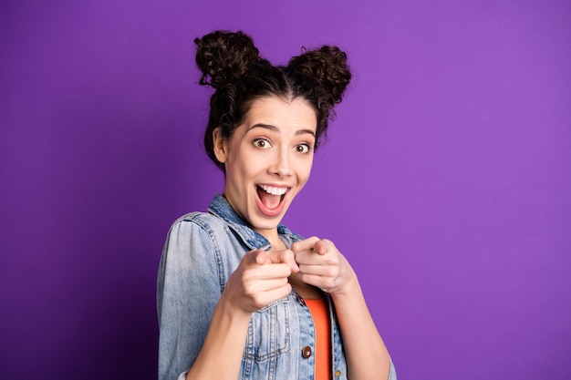 Stylish student with curly hair posing against the purple wall