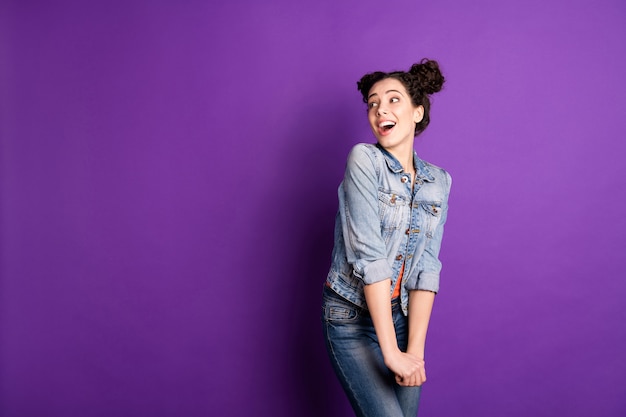 Stylish student with curly hair posing against the purple wall