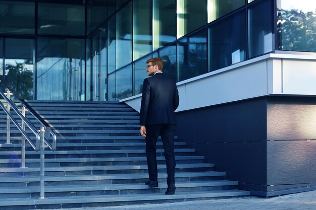 Stylish successful businessman goes up the stairs of the office building