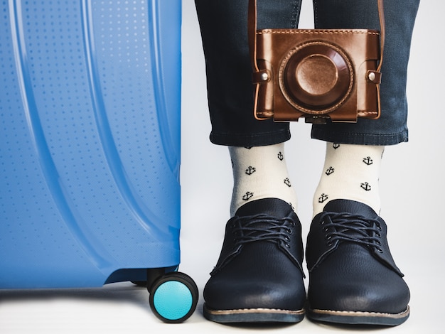 Stylish suitcase, men's legs, vintage camera and bright socks