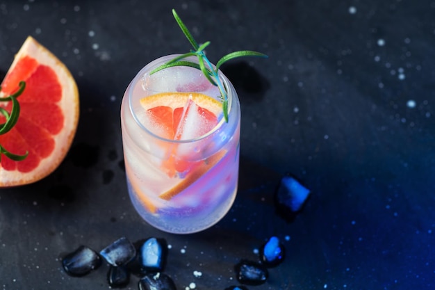 Stylish summer ice alcoholic cocktail with grapefruit and rosemary Gin and tonic copy space