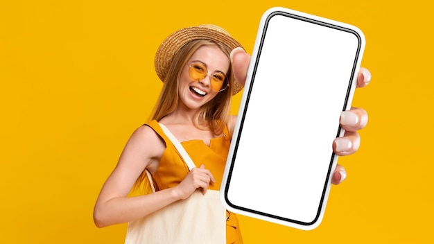 Stylish summer lady holding white tote bag and showing smartphone