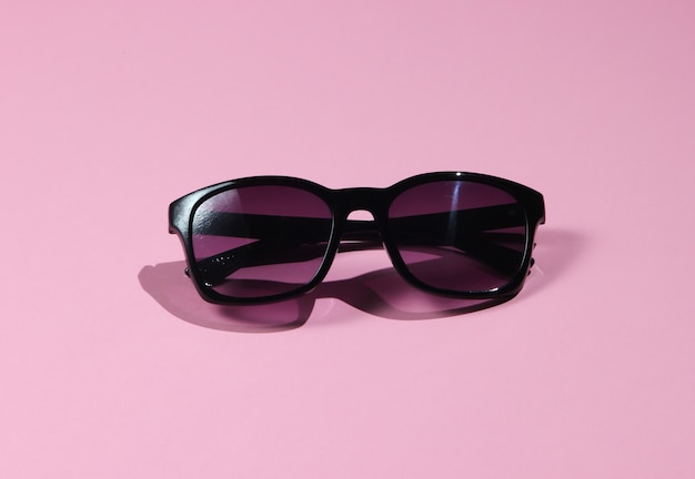 Stylish sunglasses on a pink pastel background. Fashion shot with shadows.