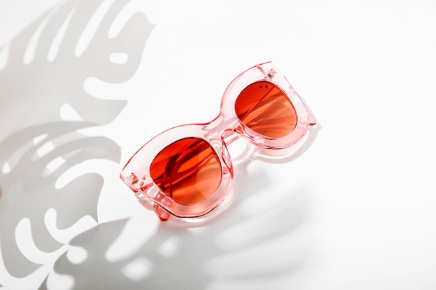 Stylish sunglasses with bright sunlight and shadow from palm leaves. summer vacation concept.