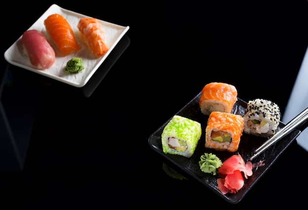 Stylish sushi sets on a black ceramic plate and  Chinese sticks. Copy space