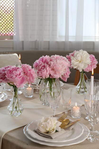 Foto tavola elegante con bellissime peonie e candele accese all'interno
