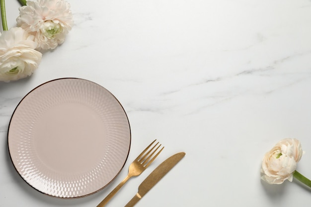 Stylish table setting with cutlery and flowers on white marble background flat lay Space for text