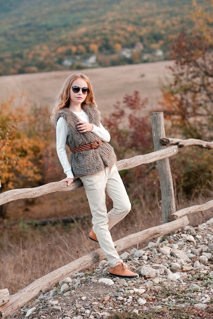 Стильная девочка-подросток позирует в сельской местности в современной одежде на открытом воздухе