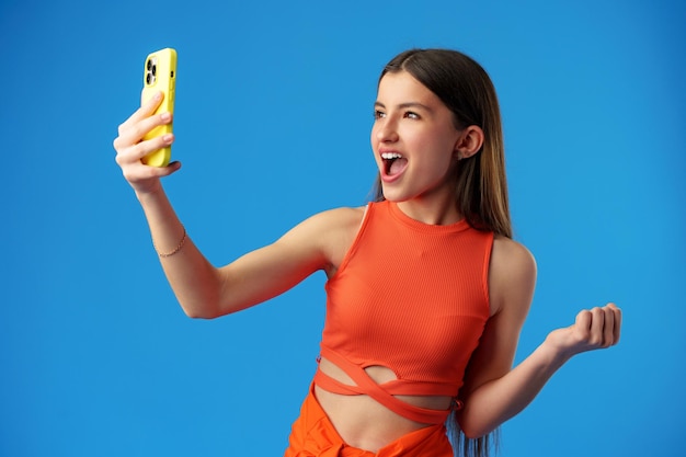 Stylish teen girl using smartphone over blue background