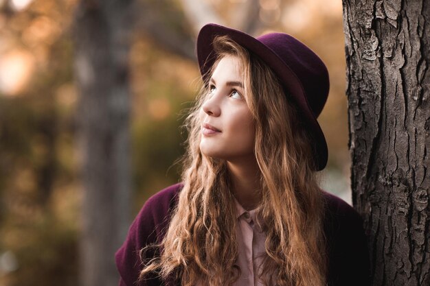 Stylish teen girl wearing felt hat and winter jacket over nature