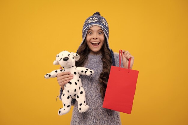 Stylish teen girl in winter warm hat with shopping sale bags kid holding purchases happy girl face positive and smiling emotions