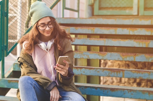 スタイリッシュな10代の少女は、スマートフォンにテキストメッセージを書き込みます。