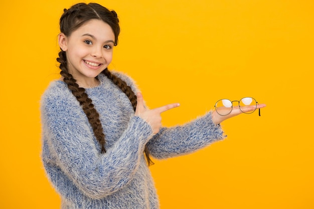 Stylish teen has good vision teenage girl presenting product vision correction treatment kid fashion and beauty small girl hold glasses childhood happiness beautiful braided long hair