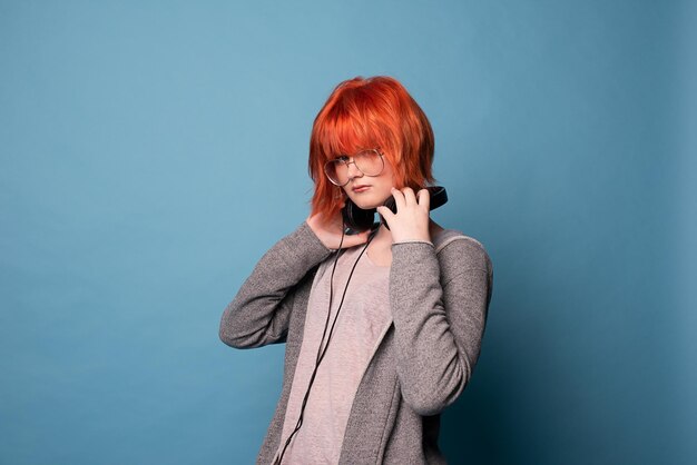 Stylish teenage girl with headphones on blue background