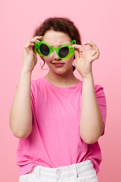 ピンクのTシャツグリーンメガネのスタイリッシュなティーンエイジャーの女の子モデルユースファッション