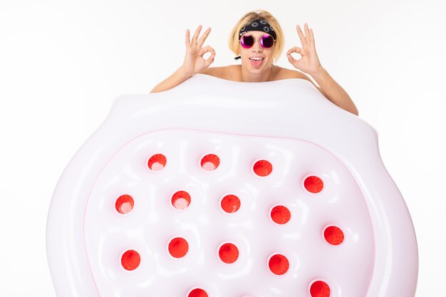 Photo stylish tourist man with an air mattress for swimming on a white wall