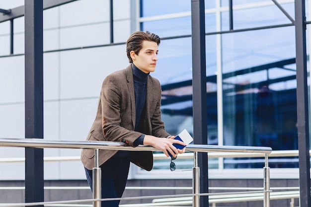 Stylish traveller in jacket with passport and tickets in urban context