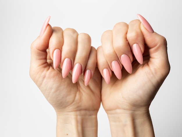 Foto unghie eleganti e alla moda, mani di giovane donna, manicure rosa su sfondo bianco.