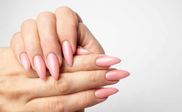 Foto unghie eleganti e alla moda, mani di giovane donna, manicure rosa su sfondo bianco.