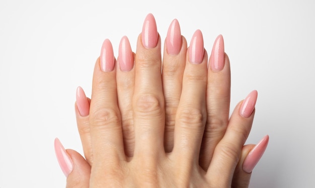 Unghie eleganti e alla moda, mani di giovane donna, manicure rosa su sfondo bianco.