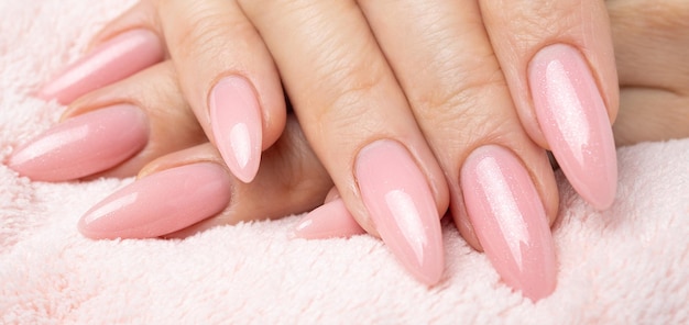 Foto unghie eleganti e alla moda, mani di giovane donna, manicure rosa su sfondo bianco.