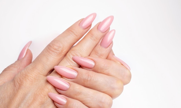 Unghie eleganti e alla moda, mani di giovane donna, manicure rosa su sfondo bianco.