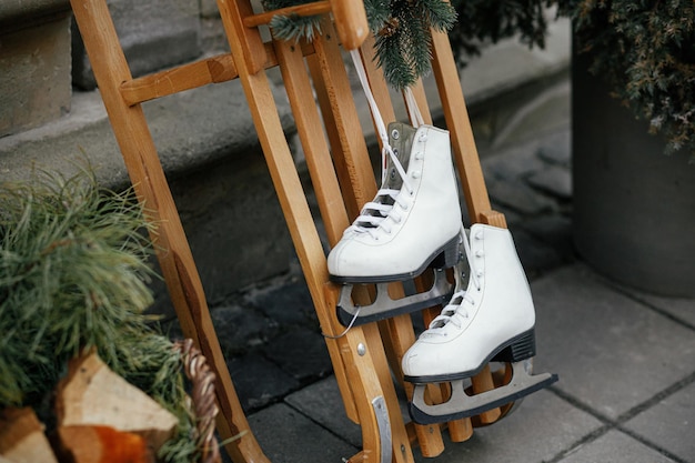 Stylish vintage ice skates and wooden sleigh at building exterior Modern christmas decor in city street Winter holidays in Europe Merry Christmas