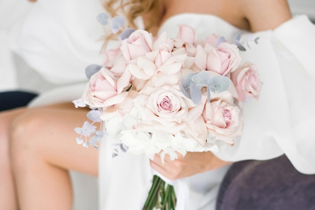 Stylish wedding bouquet of delicate pink roses in the hands of the bride closeup