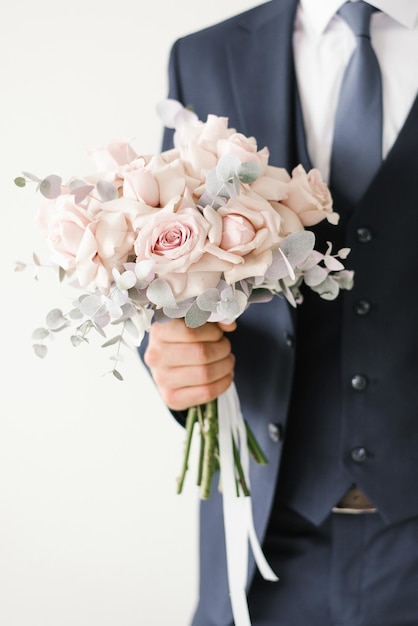 Stylish wedding bouquet of delicate pink roses in the hands of the groom closeup