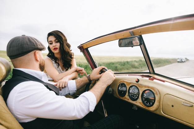 Stylish wedding couple near retro car