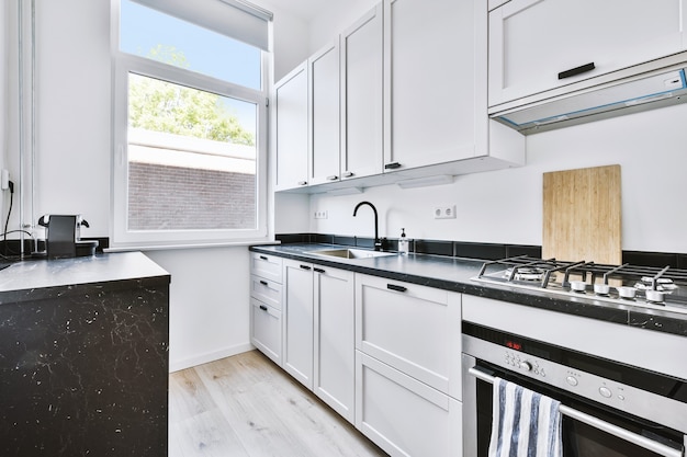 Stylish white cabinets with chrome appliances located near near window in light modern kitchen in apartment