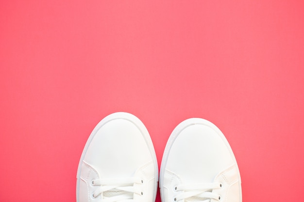 Stylish white fashion sneakers on pink .