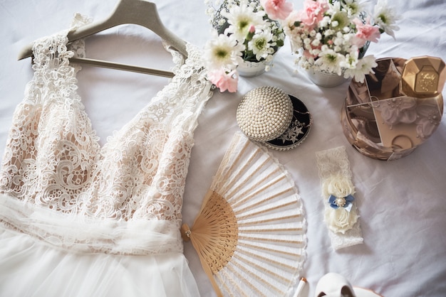 Foto scarpe da sposa bianche eleganti, vestiti, profumi, fiori e gioielli.