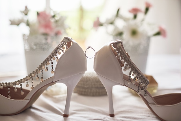 Stylish white wedding bridal shoes, perfume, flowers and jewelry.