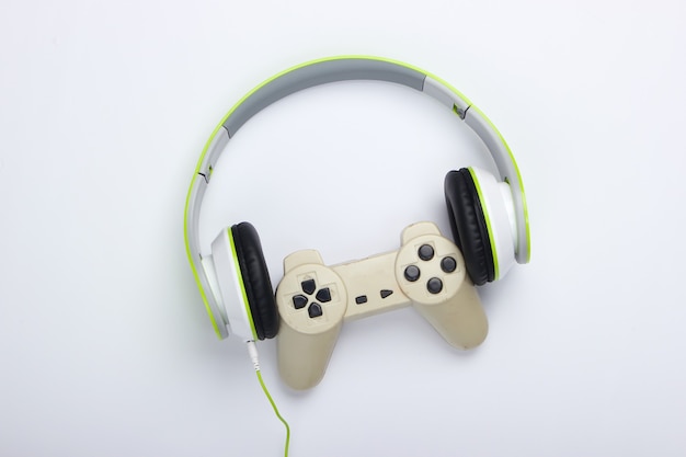 Stylish wired stereo headphones with gamepad on white surface